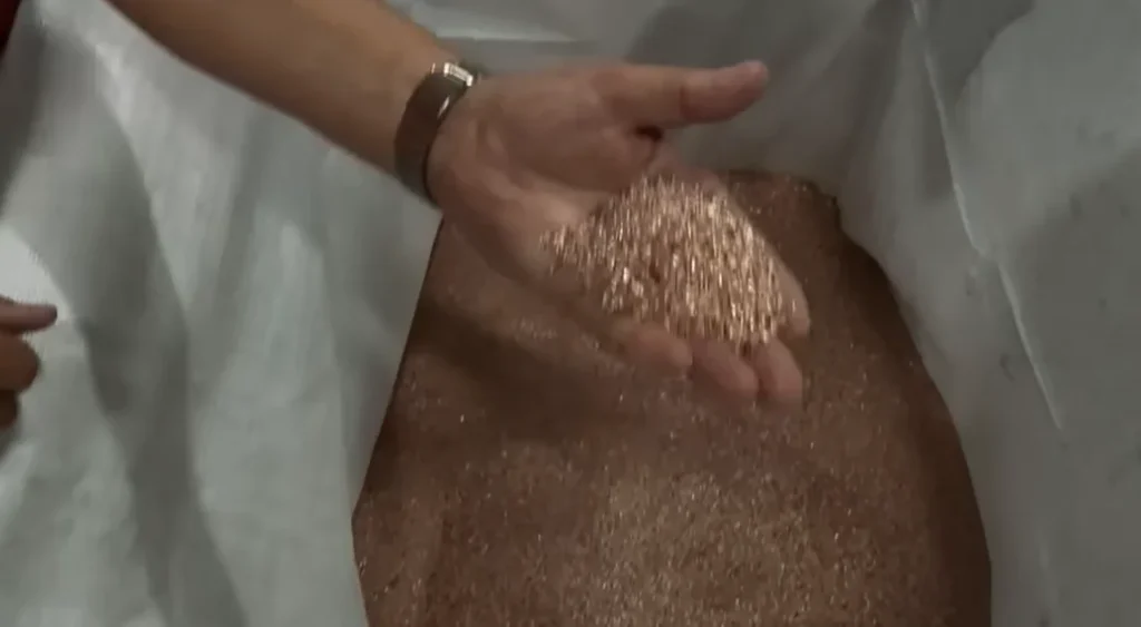 Hand holding copper granules recovered from cable recycling